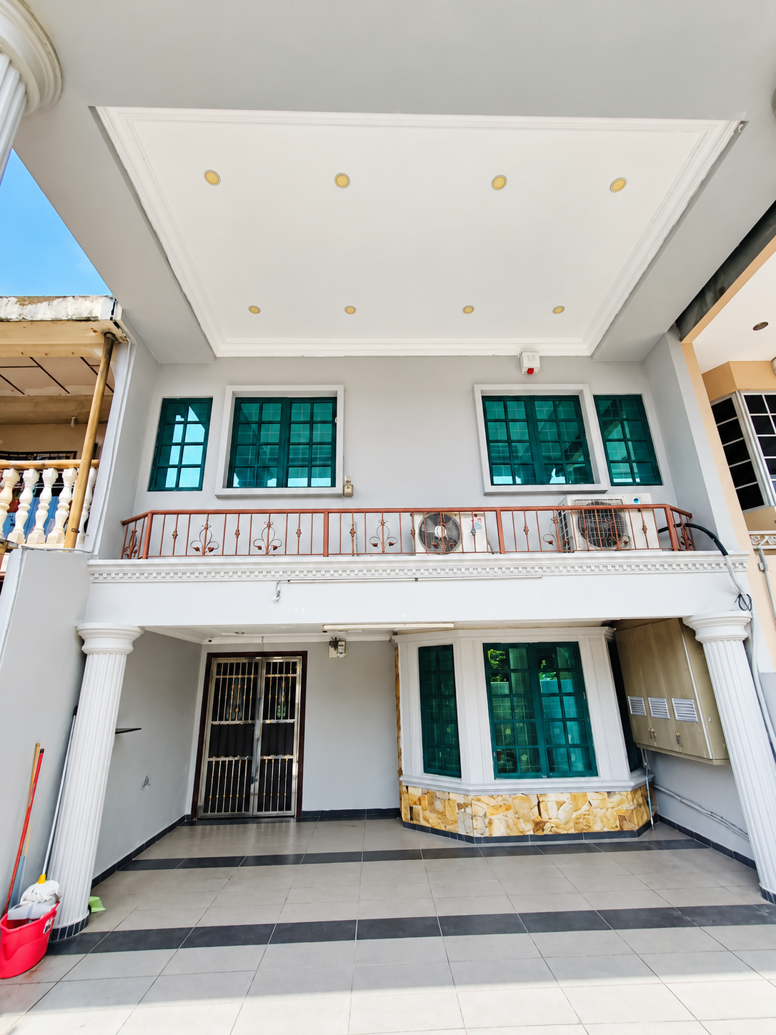 Double-storey terrace facade with covered porch, upper balcony and green-tinted windows